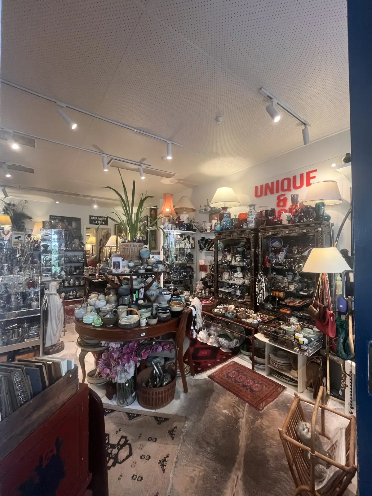 Interior of Uuli's Unique & Unusual in Manly with the red sign on the wall above shelves of treasures